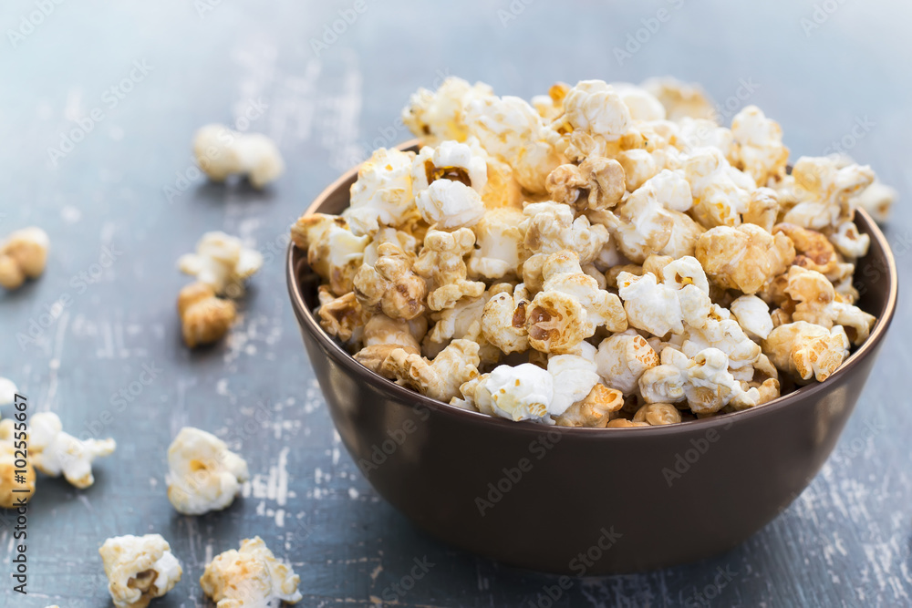 Sweet caramel popcorn in a bowl on a dark blue background Sweet caramel popcorn in a bowl on a dark blue background