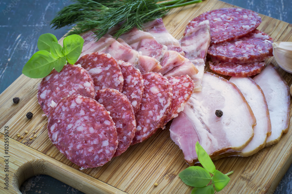 Meats - salami, bacon and greens on a cutting board Meats - salami, bacon and greens on a cutting board