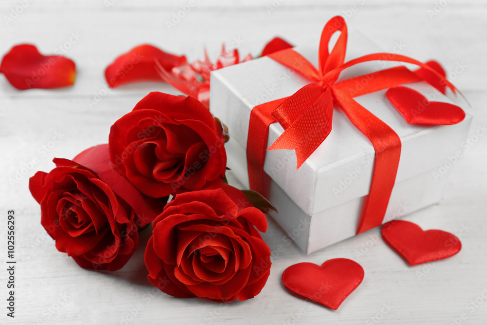 Gift box, rose flowers and decorative hearts on light wooden background Gift box, rose flowers and decorative hearts on light wooden background