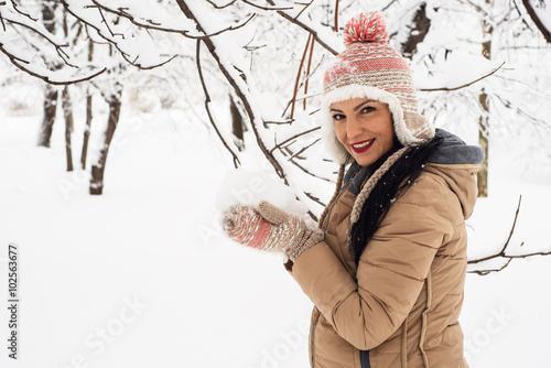 Happy woman holding snow in her hands photo