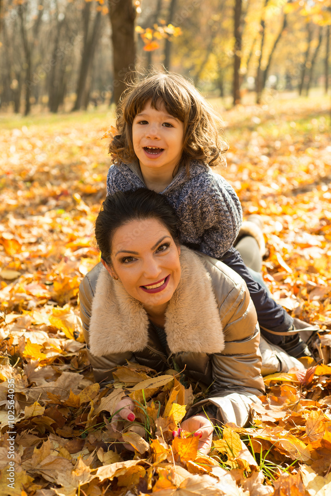 Son on top her mother in autumn park Son on top her mother in autumn park