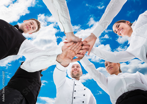 Waiters And Waitresses Stacking Hands Against Sky