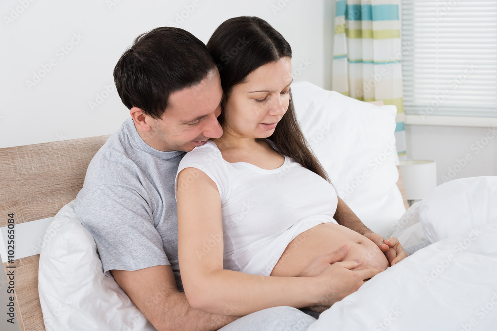 Expecting Couple Sitting On Bed Expecting Couple Sitting On Bed