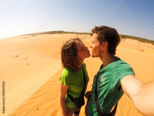 Young couple kissing on the white sand dunes in Mui Ne, Vietnam.