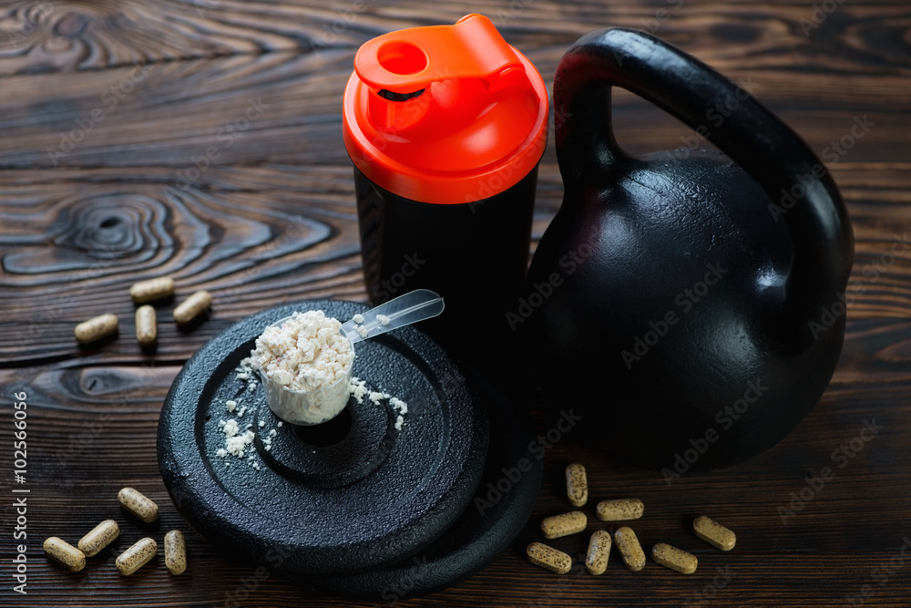 Fototapeta premium Kettle bell with shaker, scoop of protein and vitamins, close-up