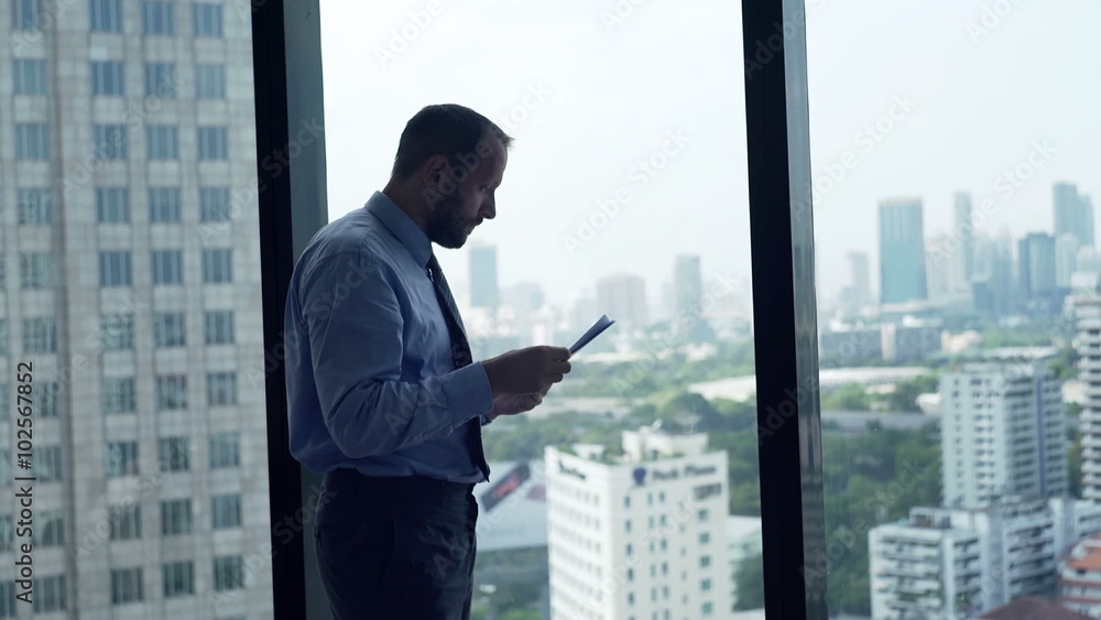 Sad, overwhelmed businessman working with documents by window at home
Sad, overwhelmed businessman working with documents by window at home