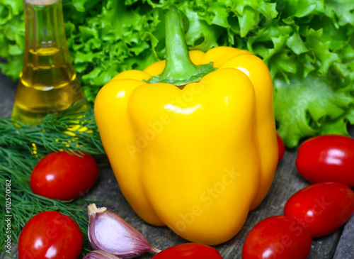 Fresh vegetables. Yellow pepper with red tomatoes and lettuce on a wooden background