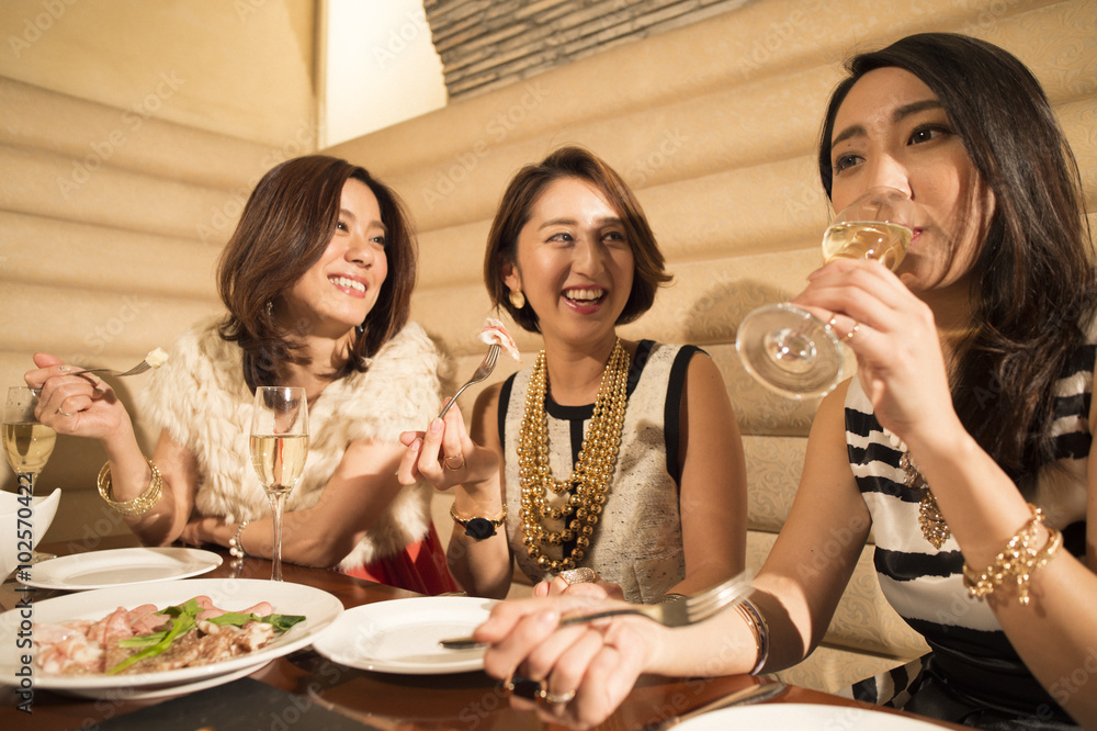 Three women are enjoying a meal in the restaurant while drinking champagne Three women are enjoying a meal in the restaurant while drinking champagne