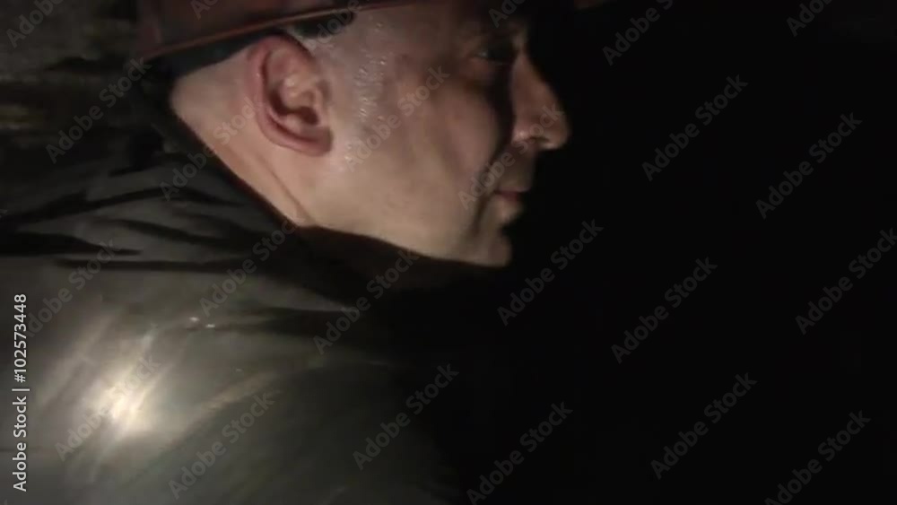 Miner Closeup, Man is Working in Coal Mine, Sweaty Man, in Safety Helmet, with Lamp on a Helmet Miner Closeup, Man is Working in Coal Mine, Sweaty Man, in Safety Helmet, with Lamp on a Helmet