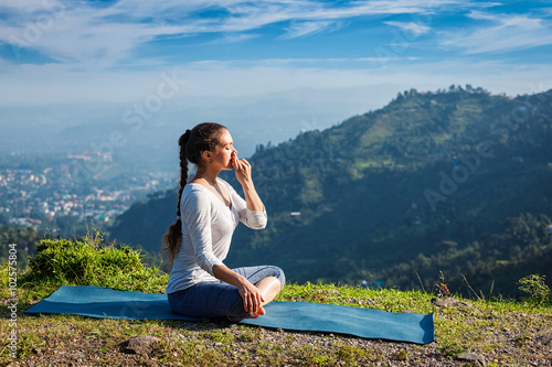 Woman practices pranayama in lotus pose outdoors