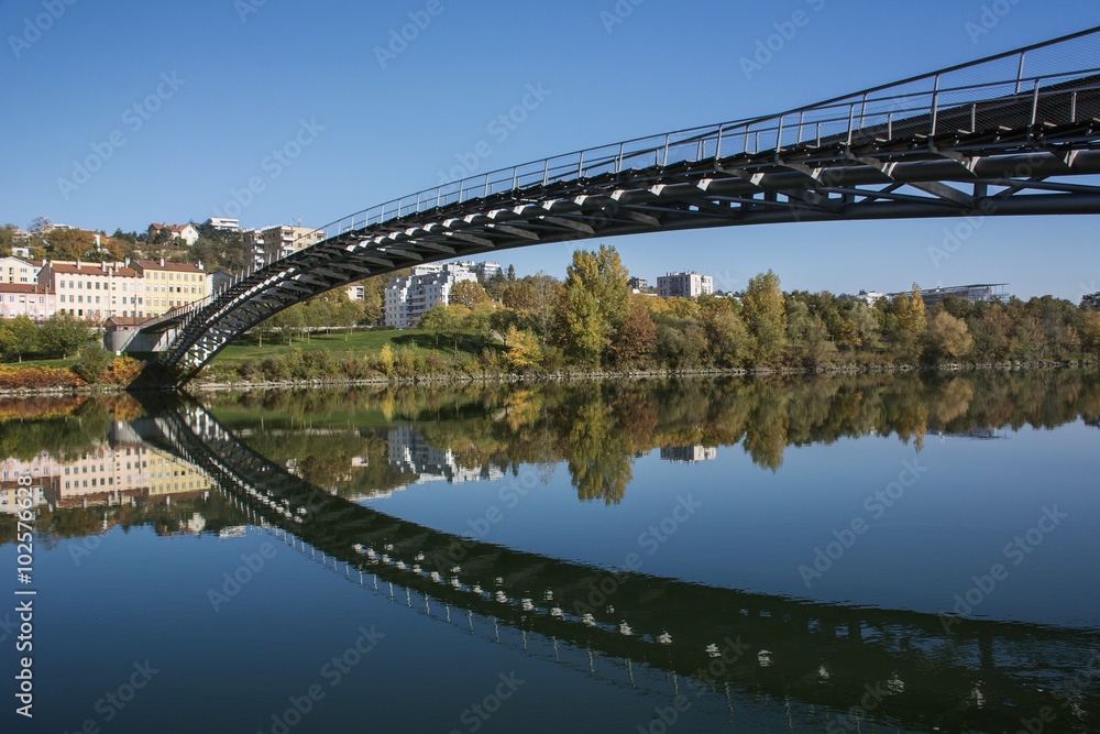 Fototapeta premium European pedestrian bridge reflected in the river in autumn