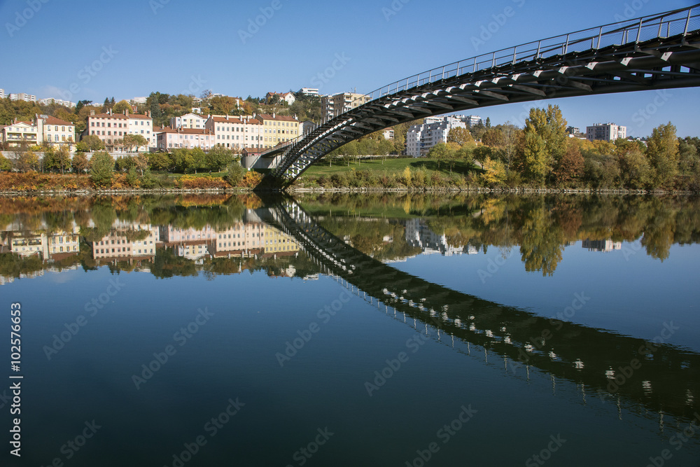 Obraz premium Modern pedestrian bridge reflected in the river in autumn