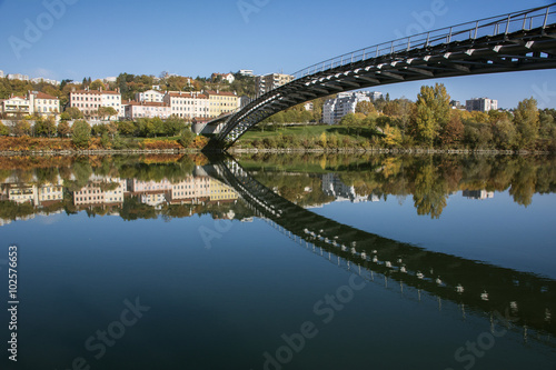 Modern pedestrian bridge reflected in the river in autumn