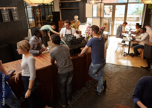 Business partners talking in their modern coffee shop busy with 