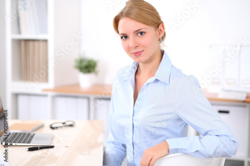 Young blonde business woman with laptop in the office. Business concept.