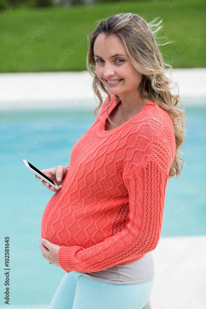 Pregnant woman touching her belly and texting