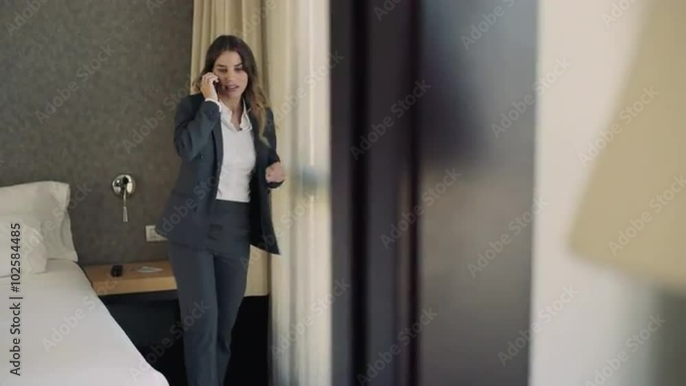 Young business woman at her hotel bedroom doing business by cell phone. At the she celebrates with enthusiasm an success or achievement. Young business woman at her hotel bedroom doing business by cell phone. At the she celebrates with enthusiasm an success or achievement.