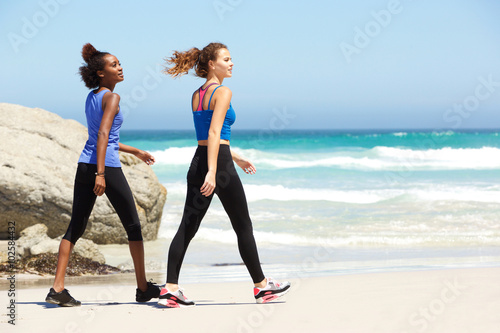Two young sporty women walking on beach