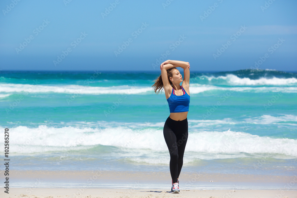 Young woman walking on beach with arms raised Young woman walking on beach with arms raised