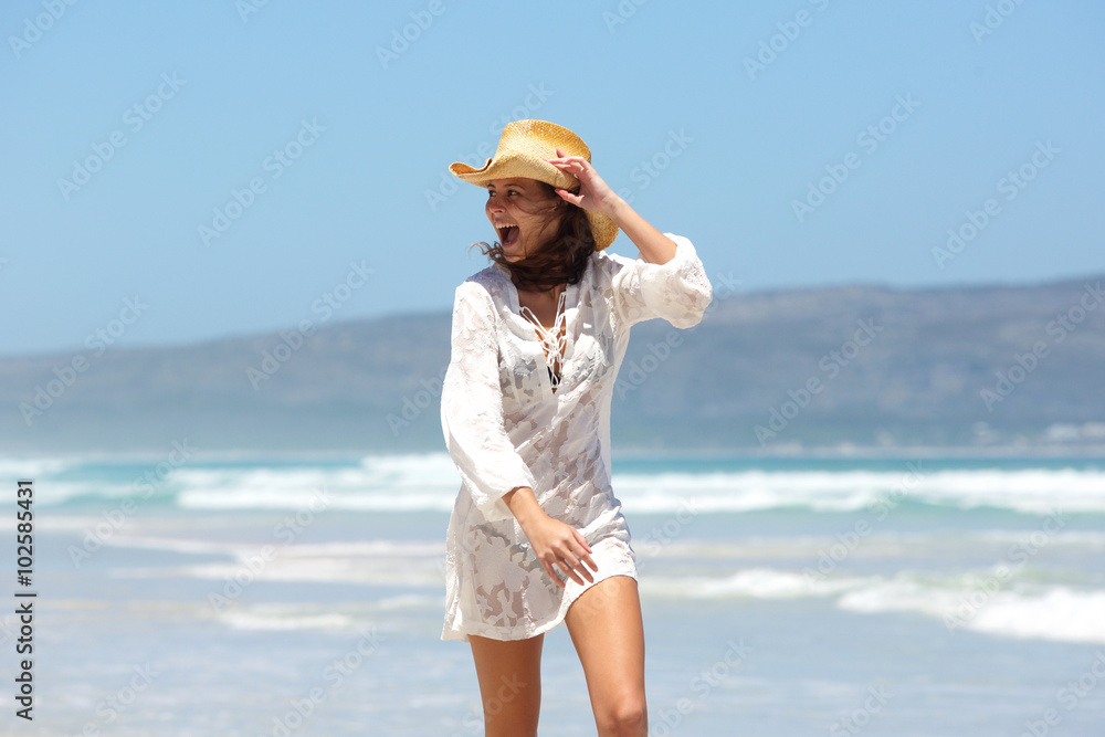 Young woman laughing with hat at the beach