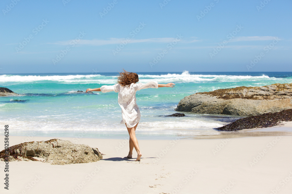Behind of young woman walking to the water on the beach