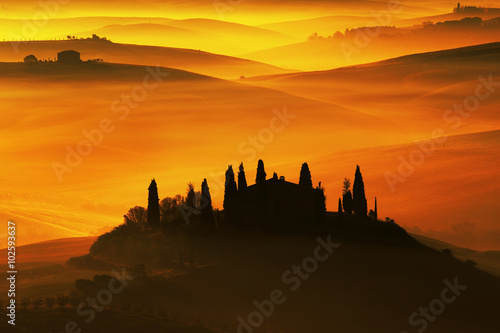 Scenic view of typical Tuscany landscape, house with hills during orange sunset, Italy