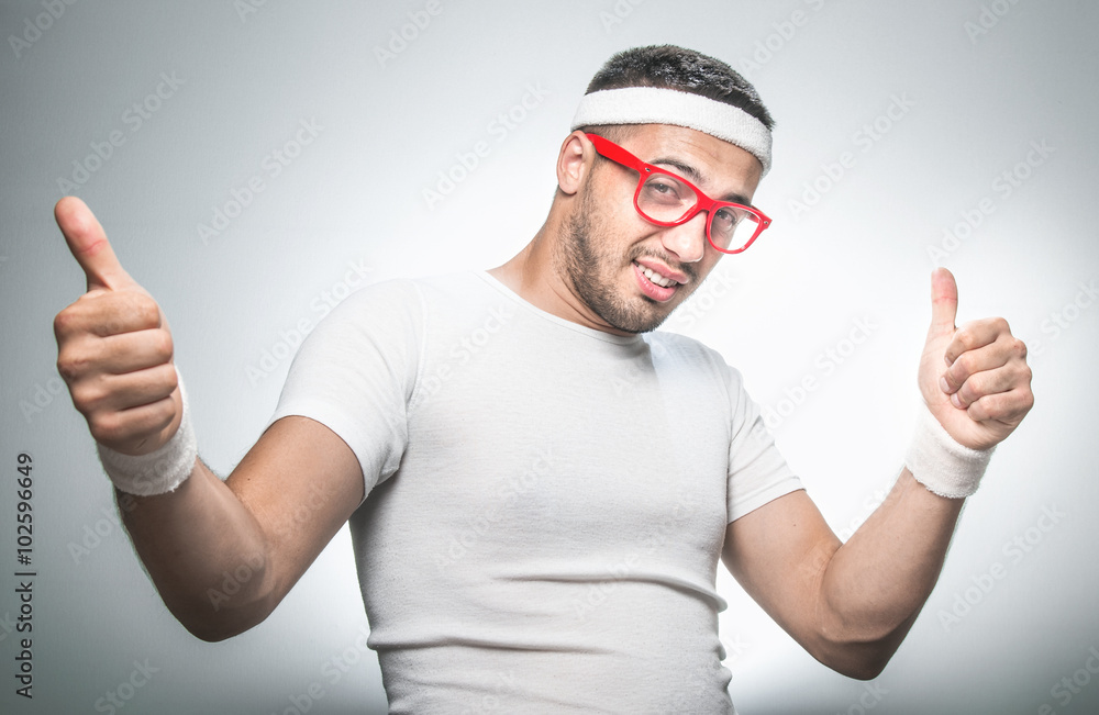 Fototapeta premium Funny nerd doing aerobics and showing thumbs up. Isolated on gray background, studio shot.