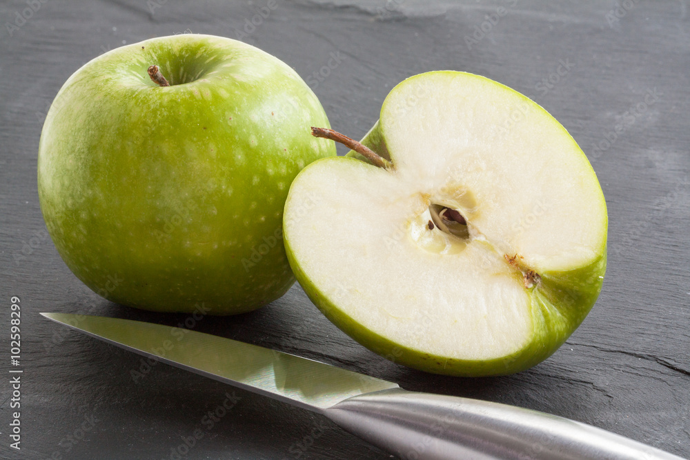 Pommes Granny-Smith et moitié sur fond ardoise Pommes Granny-Smith et moitié sur fond ardoise