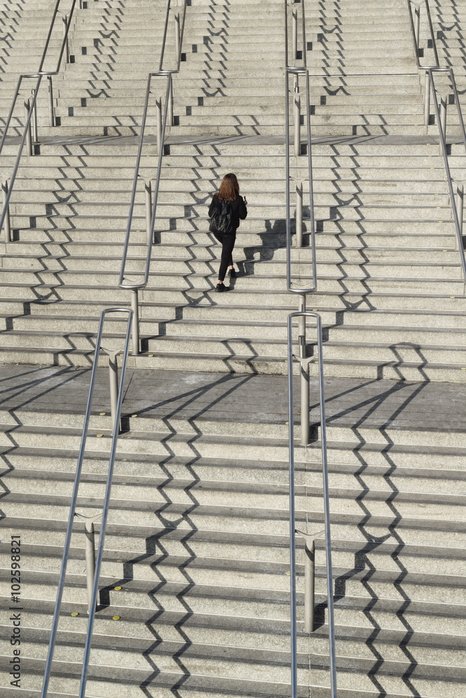 Large stairways with metal handrails and lonely person passing by