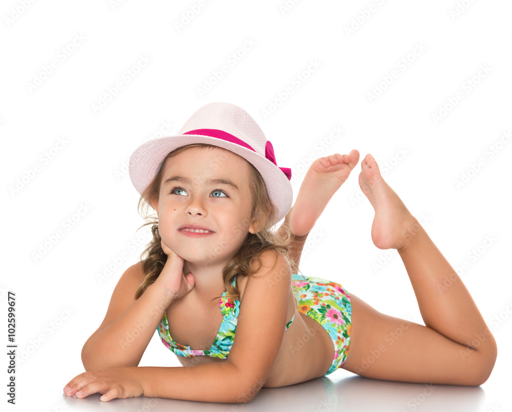 Adorable little girl in a pink hat and a bathing suit lying on the