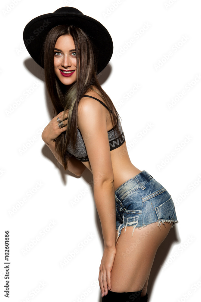 Beautiful young woman with long hair posing on wight background. Black hat. Beautiful young woman with long hair posing on wight background. Black hat.