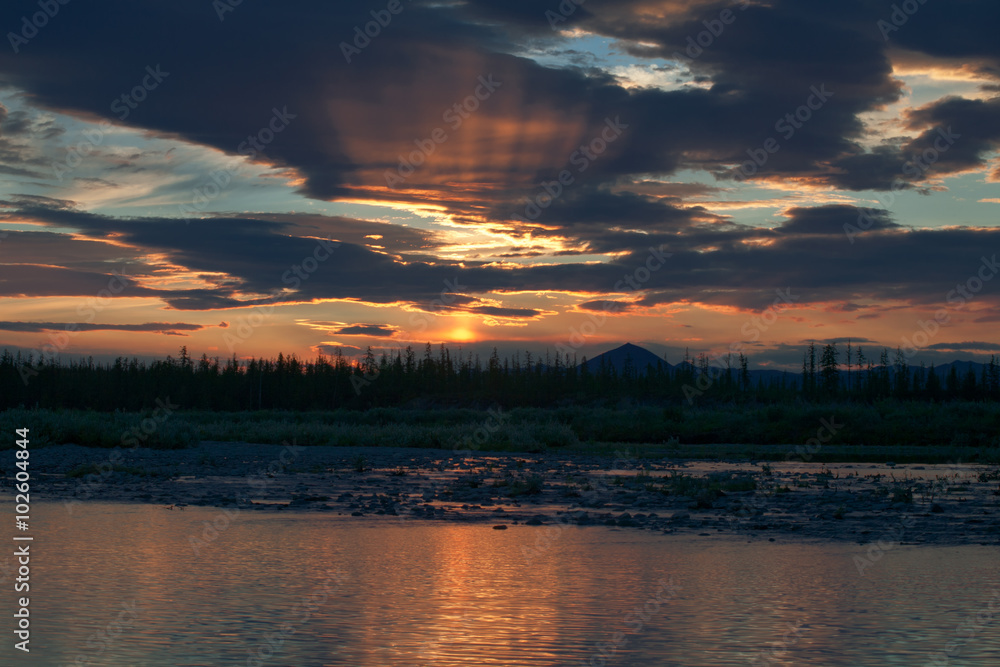 The rays of the setting sun in the clouds. Moma River. Yakutia. Russia.