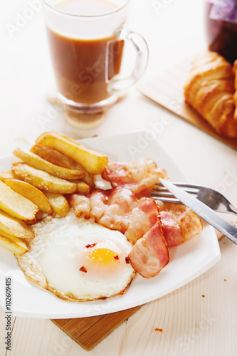 Breakfast with eggs, bacon, French fries and coffee