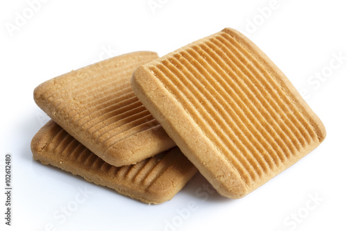 Pile of three square Italian shortbread honey and milk biscuits with ridges, isolated on white in perspective.