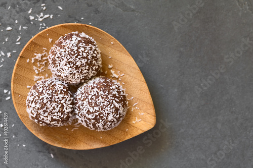 Coconut rum balls on small wooden plate, photographed overhead om slate with natural light (Selective Focus, Focus on the top of the balls) photo