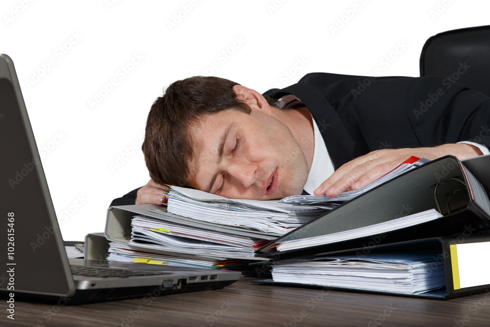 Exhausted businessman sleeping on a desk at his workplace, isolated on white background Exhausted businessman sleeping on a desk at his workplace, isolated on white background