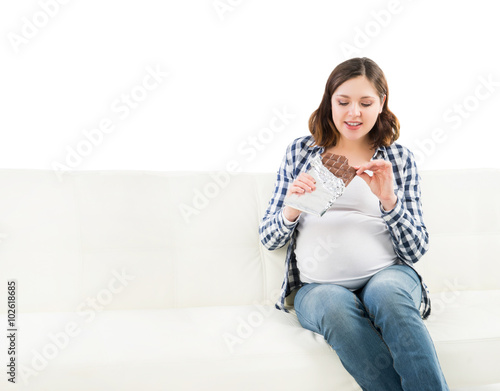Young pregnant woman eating a chocolate