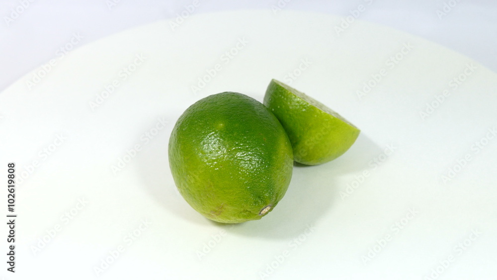 Limes, one sliced in half, fruit isolated on white background