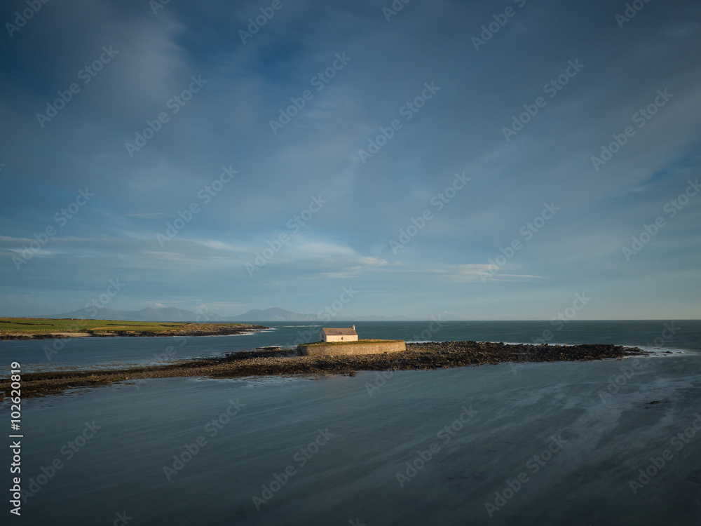 St Cwyfan's Church, Aberffraw, Anglesey, Cymru, Wales. The church in the sea with the peaks of the Llyn peninsula in the background.