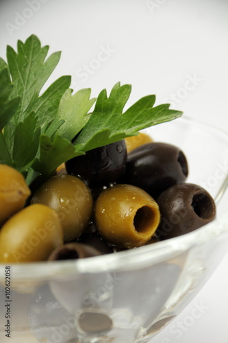 Olives. / Olives with parsley in a glass container.