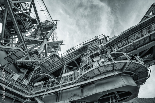 One side of huge coal mining drill machine photographed from a ground with wide angle lens. Dramatic sky in background. 