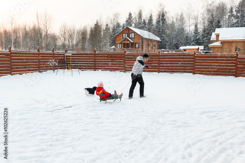 Dad daughter and dog sledding in backyard