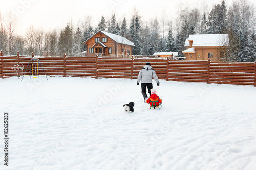 Dad daughter and dog sledding in backyard
