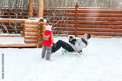 Dad daughter and dog sledding in backyard