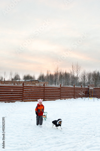 girl and dog sledding in backyard
