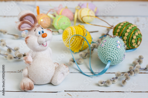Easter bunny, pussy willow and handmade Happy Easter eggs on a light wooden background