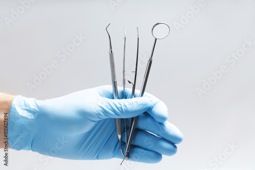 Keep dentist dental tools in the hands on a white background