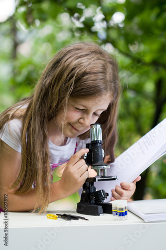 student little girl with microscope - working outside in nature