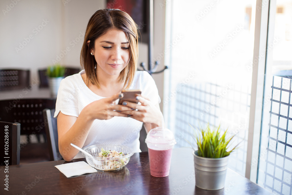 Pretty girl using smartphone in a restaurant Pretty girl using smartphone in a restaurant