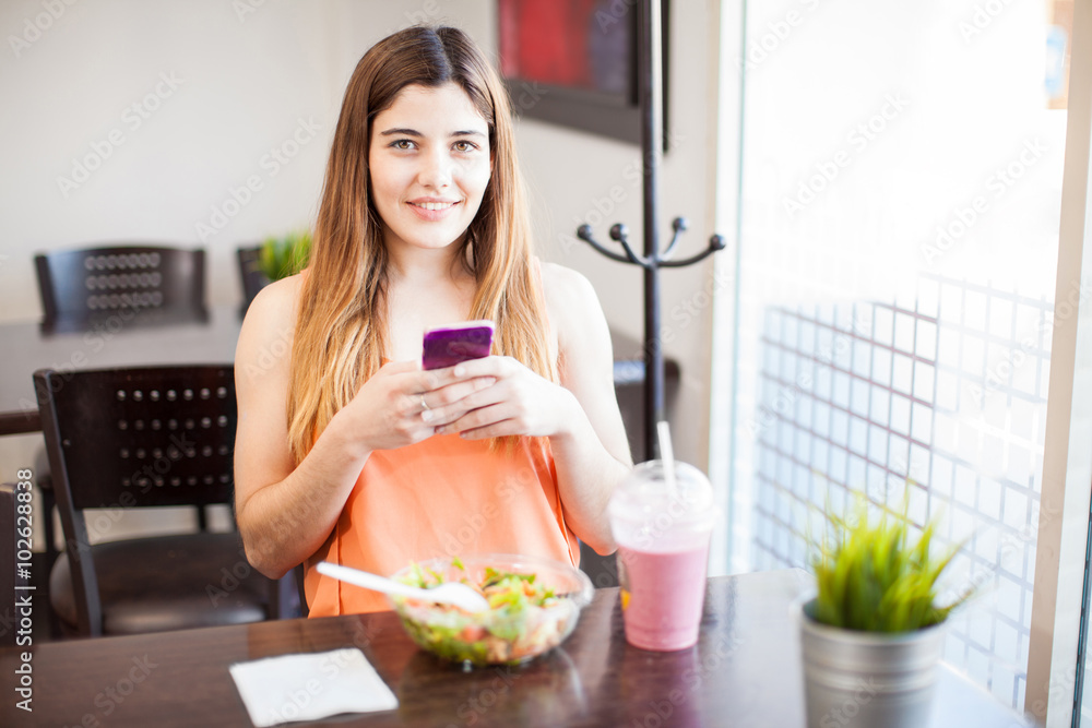Gorgeous girl using a smartphone while having lunch Gorgeous girl using a smartphone while having lunch